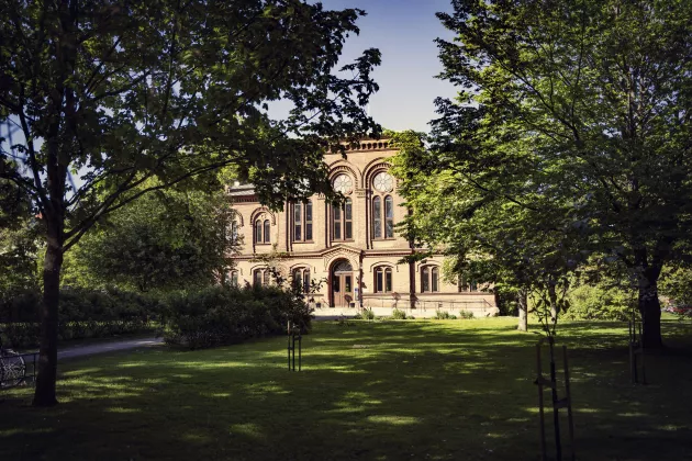 The Pufendorf Institute, and its facade in red brick and several large windows, view from a green garden. Photo.